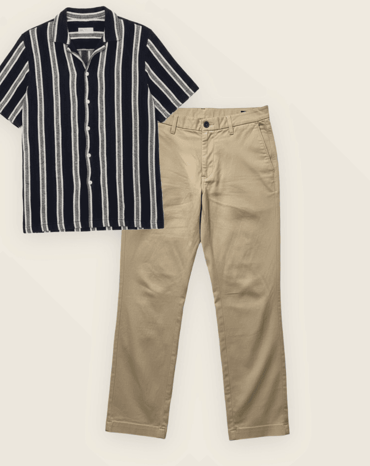 Striped camp-collar shirt and khaki chinos, flat-laid on cream paper